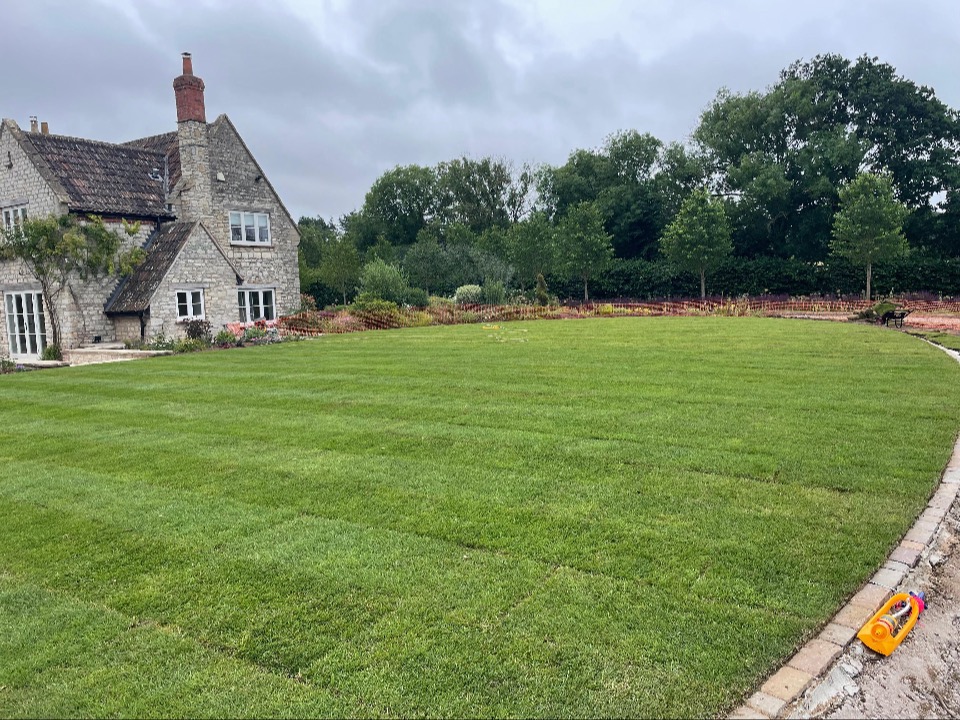 The finished garden — a level lawn and planted borders beside the period stone house