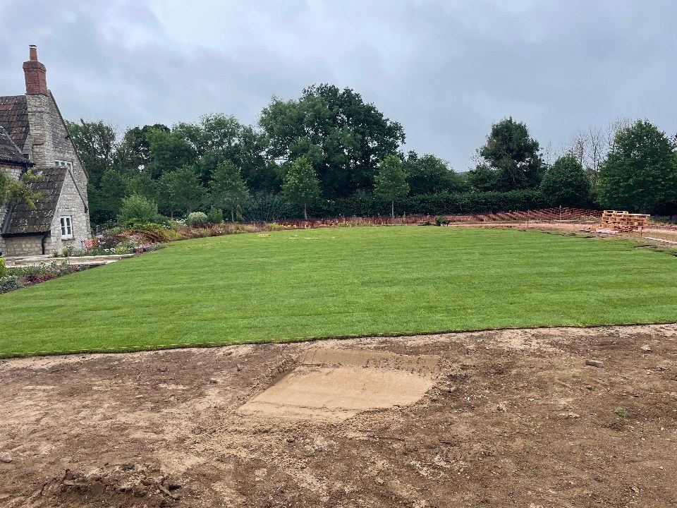 A freshly laid lawn beside a period stone cottage