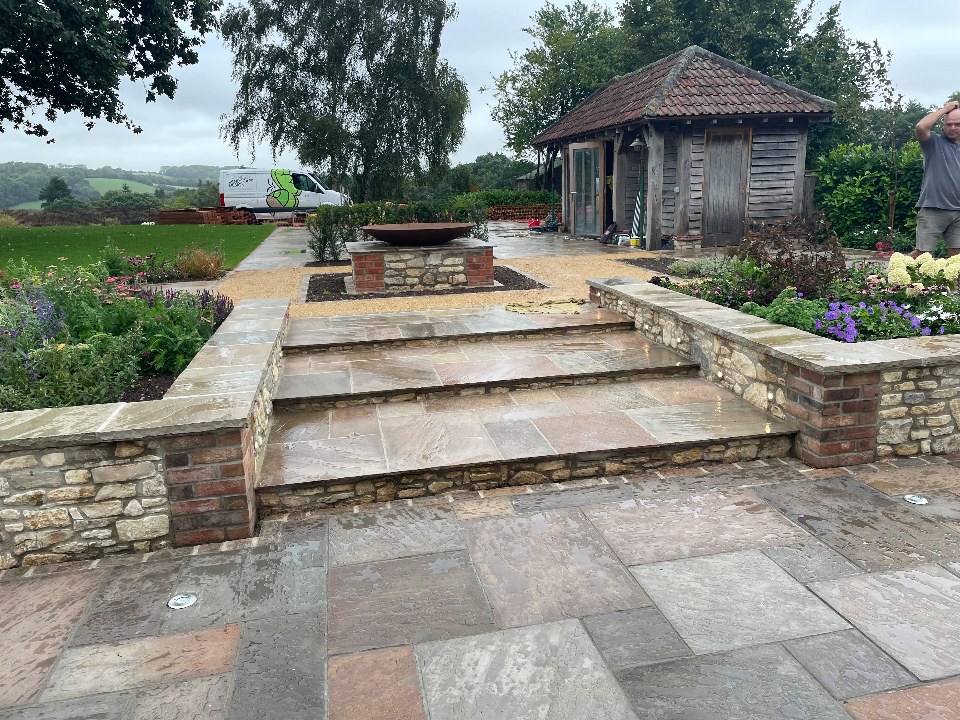 A sandstone terrace with stone-and-brick steps leading to a fire-bowl feature