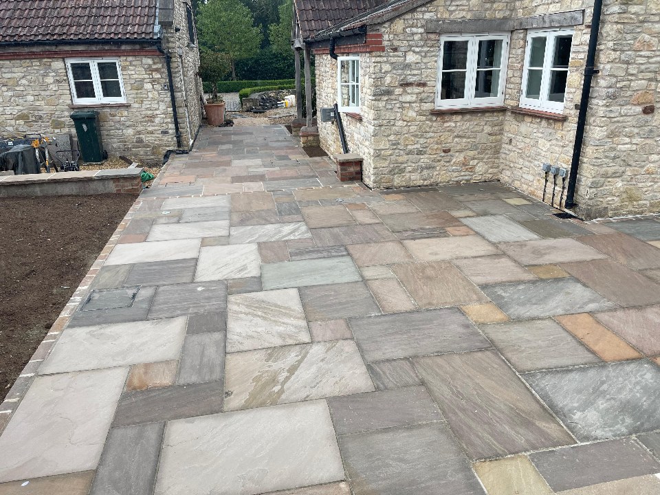 A sandstone path and patio running between two stone buildings